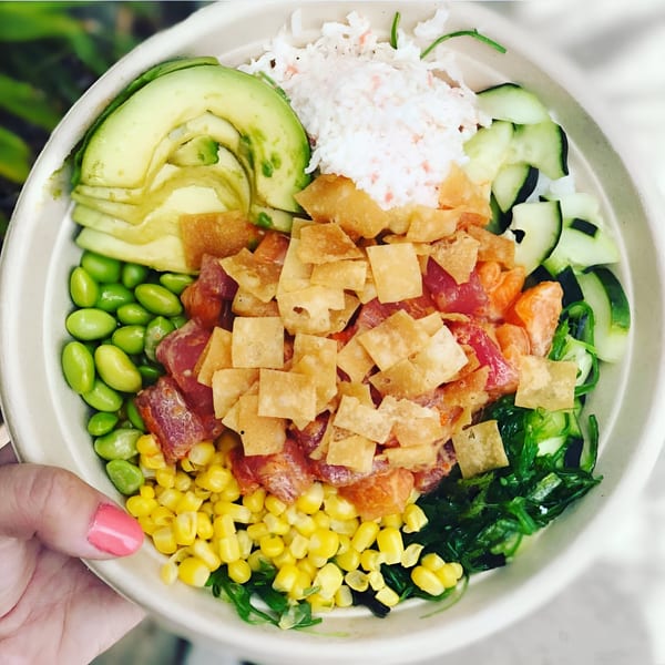 A vibrant Poke Chop poke bowl with tuna, avocado, edamame, corn, cucumber, and wonton crisps.