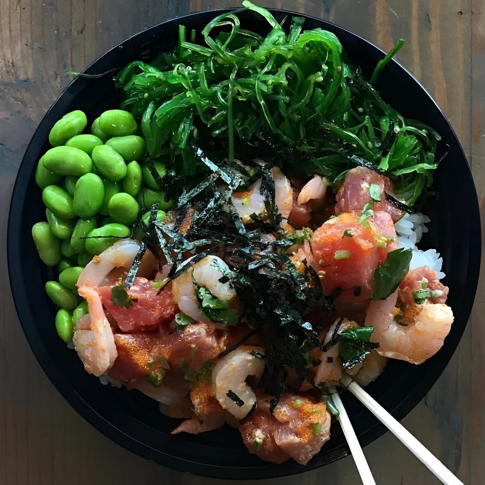 Poke Chop poke bowl with tuna, shrimp, edamame, seaweed salad, and nori on rice.
