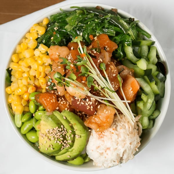A vibrant Poke Chop poke bowl with tuna, salmon, corn, edamame, avocado, seaweed, and rice.