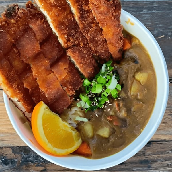 Poke Chop's katsu curry with sliced fried chicken, rice, curry sauce, and an orange slice.